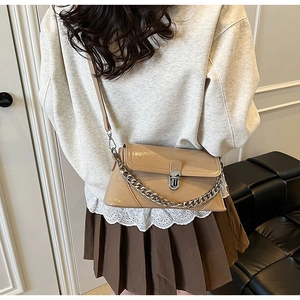 Sac bandoulière beige chic avec chaîne argentée porté par un mannequin pour l'effet de style