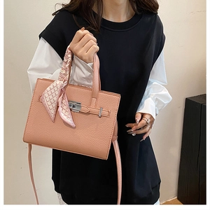 Détail du sac rose en cuir grainé avec fermoir rotatif argenté et foulard en soie