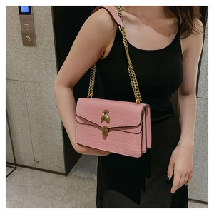 Détail du sac à bandoulière rose texture crocodile avec fermoir abeille et chaîne dorée