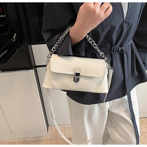 Sac à bandoulière blanc en similicuir avec chaîne argentée et fermoir porté par une femme