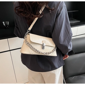 Détail d'un sac bandoulière beige avec chaîne argentée et fermoir métallique brillant