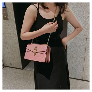 Détail du petit sac rose effet croco avec fermoir abeille dorée et bandoulière chaîne