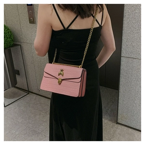 Détail du sac rose motif crocodile avec boucle abeille dorée et bandoulière en chaîne
