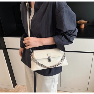 Détail du sac en cuir verni blanc cassé avec chaîne argentée et fermoir à boucle en métal