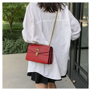 Détail du sac rouge à motif crocodile avec fermoir abeille doré et bandoulière chaîne