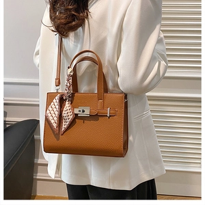 Détail du sac cabas marron à motif litchi avec fermoir rotatif et foulard décoratif