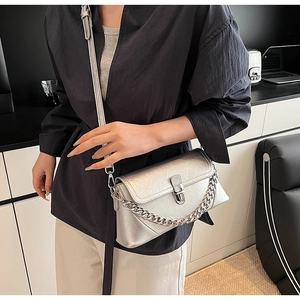 Détail du sac bandoulière argenté métallisé avec chaîne décorative et texture froissée