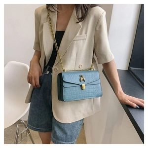 Détail du sac bleu clair à texture crocodile avec fermoir abeille dorée et chaîne