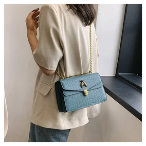 Détail du sac bleu clair à texture crocodile avec fermoir abeille et chaîne dorée