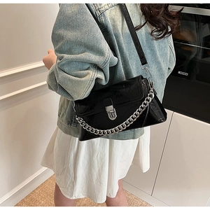 Détail d'un sac bandoulière noir verni avec chaîne argentée et fermoir métallique