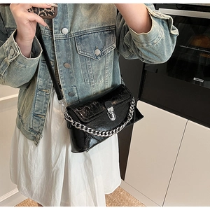 Détail du sac brillant noir avec chaîne argentée et finition en vernis texturé