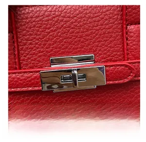 Détail du sac en cuir rouge à texture litchi avec fermoir rotatif en métal argenté