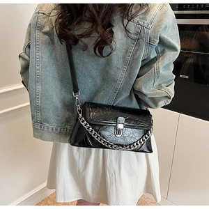 Détail du sac noir brillant à texture froissée avec fermoir en U et chaîne argentée