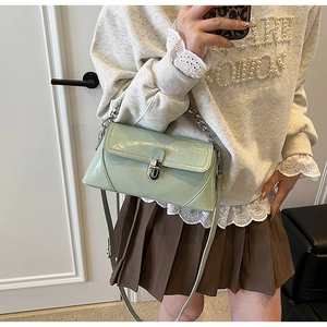 Gros plan d'un sac bandoulière en cuir verni vert menthe avec fermoir rotatif métallique