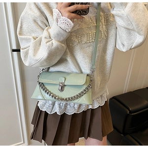 Détail du sac bandoulière en cuir verni vert clair avec chaîne argentée et fermoir