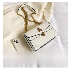 Détail du sac blanc motif crocodile avec fermoir abeille doré et bandoulière chaîne