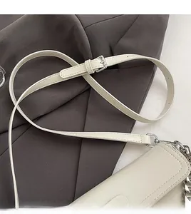 Gros plan sur la bandoulière réglable avec chaîne argentée et boucle sur le sac beige