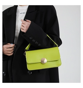 Detailed shot of vibrant lime green PU leather bag with large gold circular metal buckle