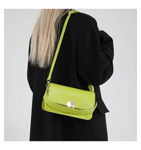 Détail du sac bandoulière en cuir vert citron avec boucle ronde en métal doré sur modèle