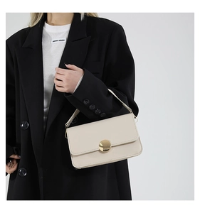 Détail du sac à bandoulière en cuir beige avec une grande boucle en métal doré rond