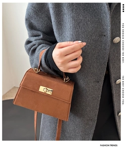 Detailed view of a brown suede handbag with a classic gold-tone rectangular swivel lock