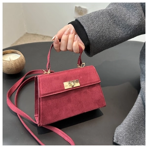 Détail d'un sac bandoulière bordeaux en daim avec fermoir doré élégant et texture raffinée