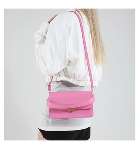 Détail d'un sac bandoulière rose avec fermoir magnétique doré et cuir PU lisse