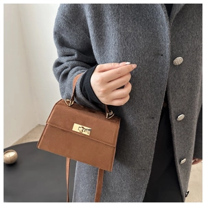 Détail d'un petit sac carré en daim marron avec fermoir tournant en métal doré chic