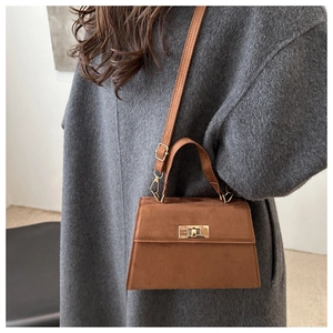 Détail du sac à main en daim caramel avec fermoir tournant doré sur un manteau