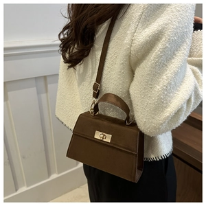 Brown faux suede crossbody bag with gold lock shown on white tweed jacket outfit