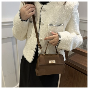 Détail du sac à bandoulière en daim marron foncé avec fermoir doré et sangle assortie