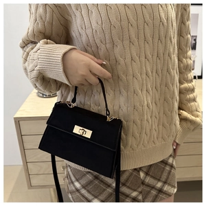 Detailed close-up of a vintage black matte trapezoid handbag with gold metal clasp detail