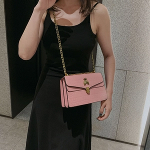 Sac bandoulière rose gaufré croco avec boucle abeille dorée et chaîne sur modèle