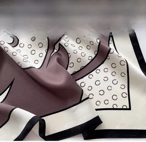 Détail des coutures fines et de la texture satinée soyeuse d'un foulard carré imprimé