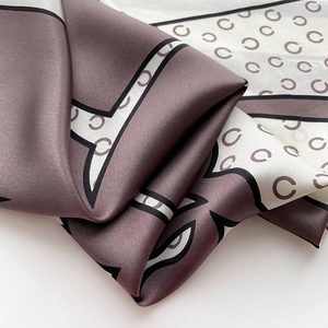 Gros plan détaillé de l'écharpe en soie avec imprimé motif C et texture lisse et soyeuse