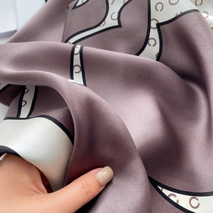 Détail du foulard en soie mauve et crème avec motif élégant en C et texture lisse et brillante