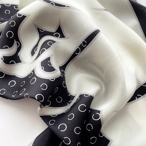 Vue détaillée d'un foulard carré en soie avec motif imprimé noir et blanc et logo chic