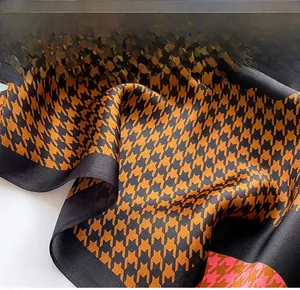 Close-up of black and orange houndstooth silk scarf showing fine edge stitching detail