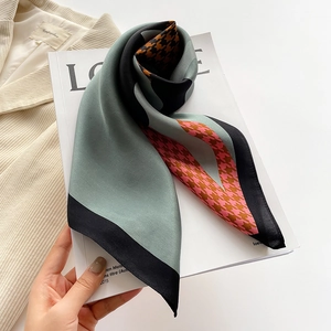 Detail of silk scarf with houndstooth pattern and mint green panels on a magazine
