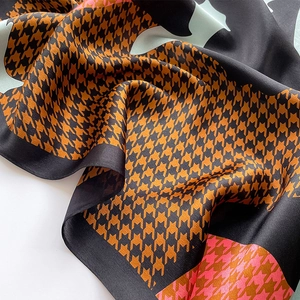 Close-up of silk scarf showing houndstooth pattern and smooth draping texture in caramel