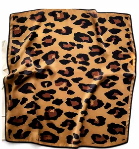 Detailed view of leopard print silk scarf with black stitched edges and glossy texture
