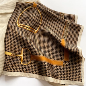 Detail of silk square scarf featuring houndstooth pattern and golden horsebit motif
