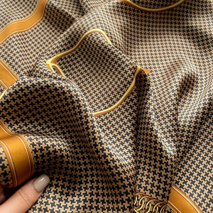 Close-up of silk scarf showing elegant houndstooth pattern and golden chain detail