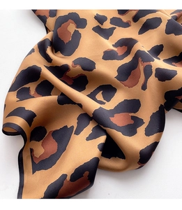 Macro shot of silk leopard print scarf showing detailed texture and rolled edges