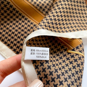 Detail of 100% mulberry silk scarf showing houndstooth pattern and care label details