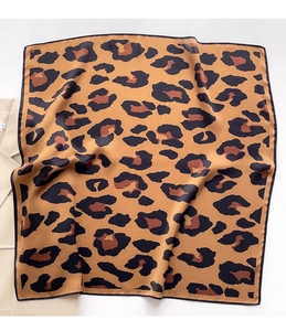 Detail of leopard print silk scarf with brown tones and black border on beige fabric