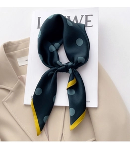 Detail of teal silk scarf with grey polka dots and yellow hem on a beige blazer