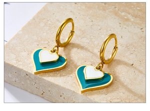 Macro detail of gold layered heart drop earrings on natural stone background