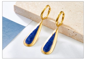 Detailed macro view of gold-plated waterdrop earrings with sparkly blue resin and green glitters