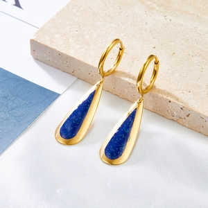 Elegant gold teardrop earrings with blue glitter resin inlays on a white satin background
